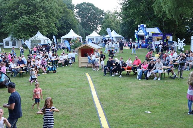 Menschen bei einem Gewerbefest im Freien mit Zelten und Sitzgelegenheiten.