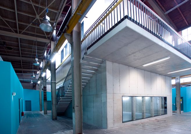 Innenansicht eines modernen Industriegebäudes mit Betonwänden, Treppe und blauen Wänden.