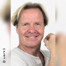 Porträt eines lächelnden Mannes mit hellem Haar vor weißem Hintergrund.