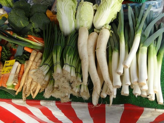 Gemüsestand auf einem Wochenmarkt mit Lauch, Rettich, Brokkoli und Karotten.