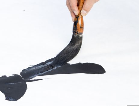 Eine Hand mit Pinsel, der einen Pinselstrich beginnt