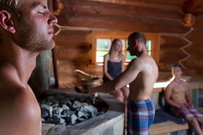 Menschen entspannen in einer Sauna mit Holzwänden.