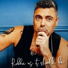 Mann mit Tattoos und Bart stützt sein Kinn auf die Hand, vor blauem Hintergrund. Text: 'Robbie as it should be'.