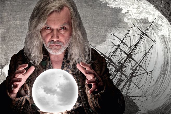 Ein Mann mit langen grauen Haaren hält eine leuchtende Kristallkugel vor einem Hintergrund mit einem Schiff in einem Sturm.