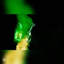 Gitarrist in grünem und gelbem Lichtnebel auf der Bühne.