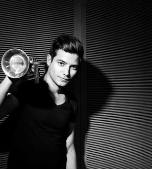 Schwarz-weiß Foto eines Mannes mit Trompete vor einer geriffelten Wand.