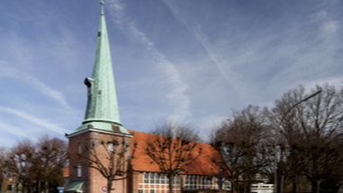 Kirche St. Johannis in Hamburg-Eppendorf mit spitzem Turm und rotem Dach.