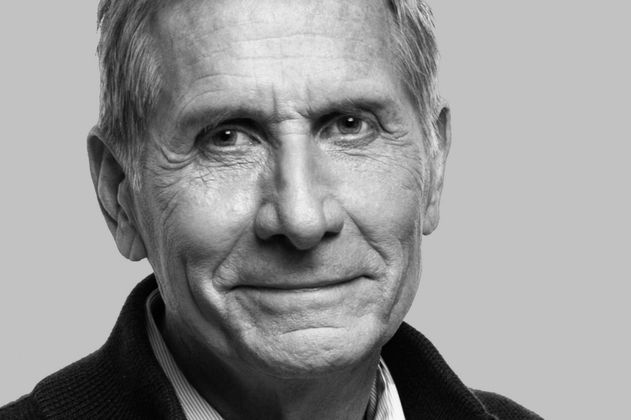 Black-and-white portrait photo of an older male-identified person with short hair and a dark collar.