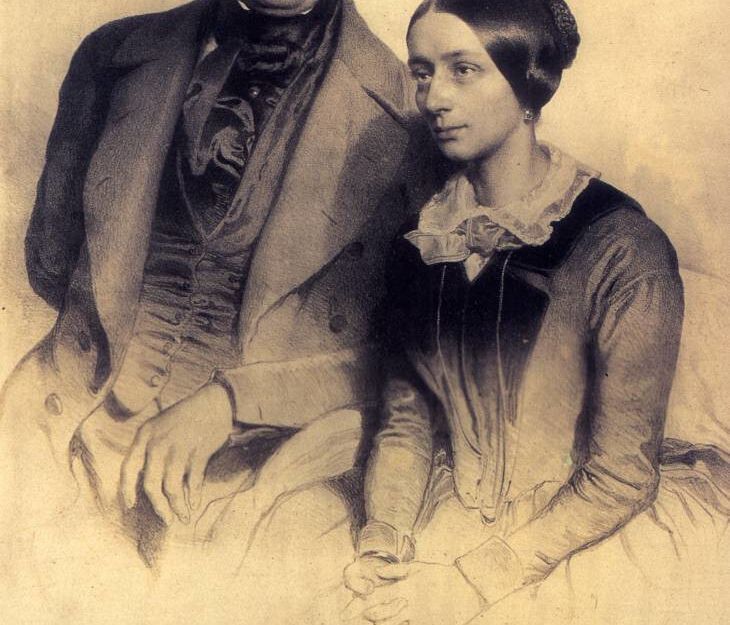 Ein historisches Porträt von Robert und Clara Schumann, das sie nebeneinander sitzend zeigt, mit handschriftlicher Widmung darunter.