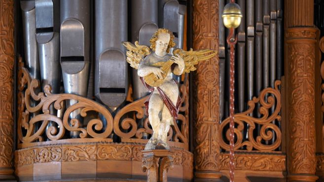Ein Engel mit einer Laute vor Orgelpfeifen.