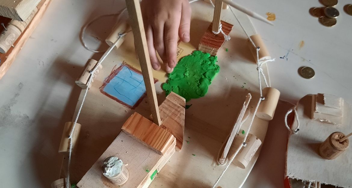 Kind baut Modellschiff aus Holz und Korken.