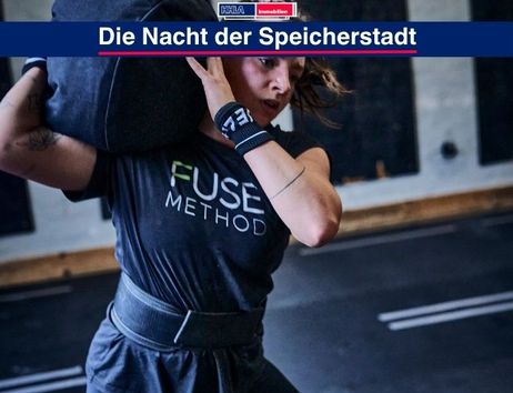 Eine Frau hebt einen schweren Sandsack in einem Fitnessstudio.