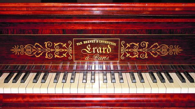 Nahaufnahme eines Érard-Klaviers mit dekorativem Holz und Tasten.