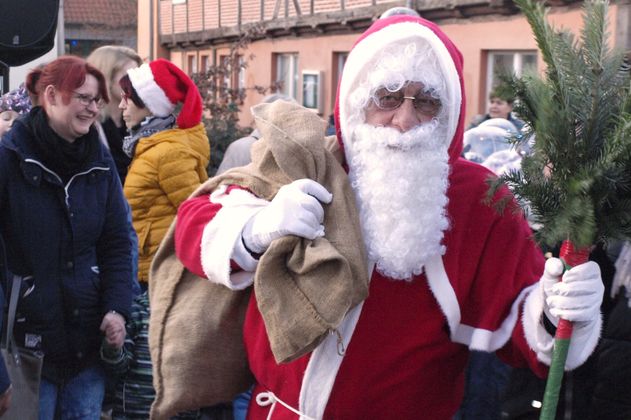 Weihnachtsmann mit Sack und Tannenzweig auf einem Weihnachtsmarkt.
