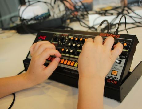 Kinderhände bedienen einen kleinen Synthesizer