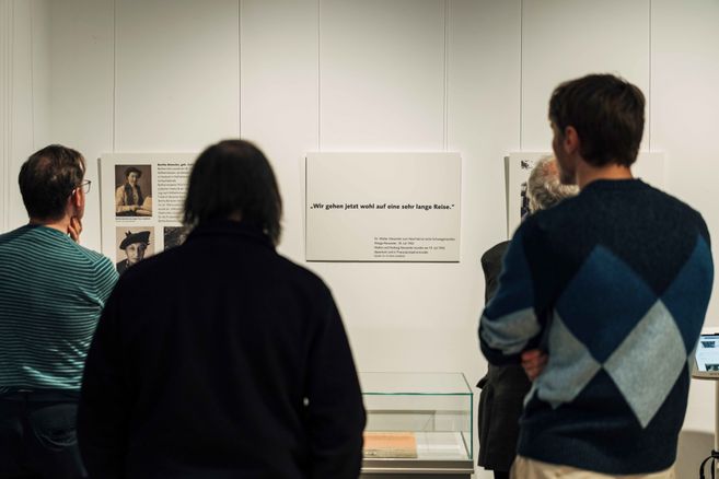 Drei Menschen stehen vor Tafeln mit Text in der Ausstellung