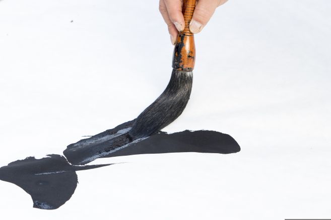 Eine Hand mit Pinsel, der einen Pinselstrich beginnt