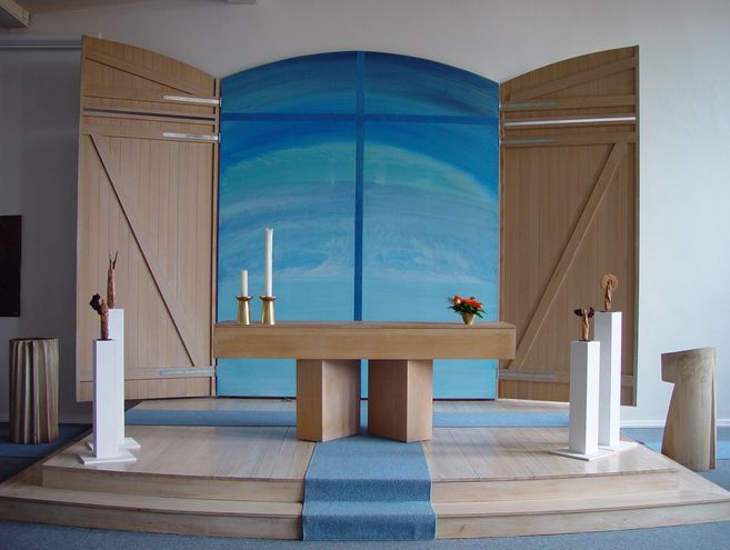 Moderner Kirchenaltar mit blauem Hintergrund und Holzverkleidung.
