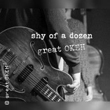 Schwarz-weiß Foto eines Gitarristen mit einer E-Gitarre, im Hintergrund ein Kontrabass. Text: 'shy of a dozen great OKEH'.