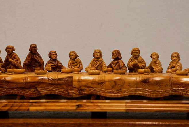 Detail aus der Adventskirche der Kirchengemeinde Hamburg-Schnelsen: geschnitzte Figuren an einem langen Tisch, vermutlich ein Abendmahlsmotiv.