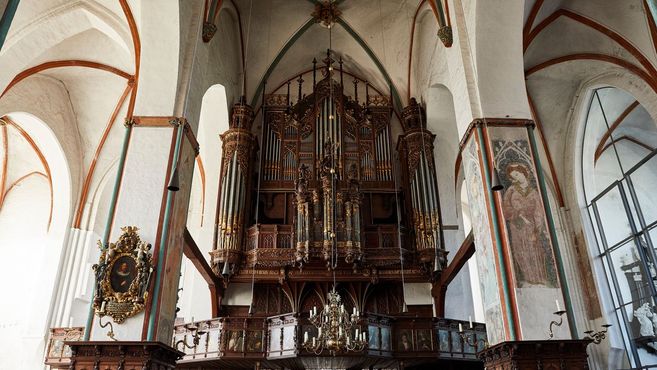 Eine große, kunstvoll verzierte Orgel in einer Kirche mit hohen Decken und gotischen Bögen.
