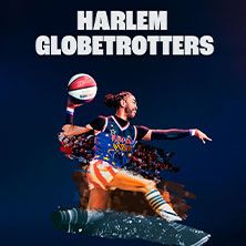Ein Spieler der Harlem Globetrotters in Aktion mit einem Basketball vor blauem Hintergrund.