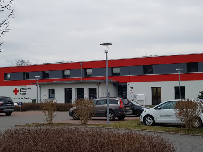 Gebäude des Deutschen Roten Kreuzes mit geparkten Autos davor.
