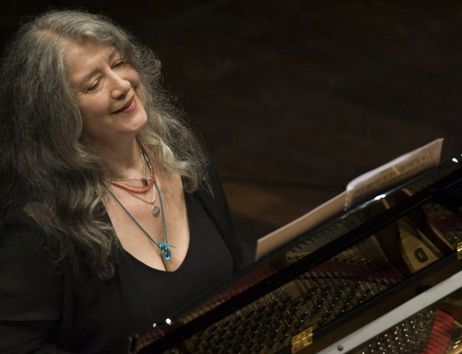 Eine Frau spielt lächelnd Klavier auf einer Bühne.