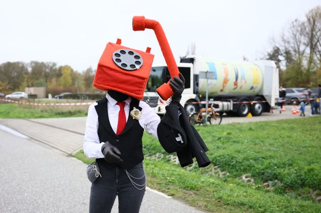 Ein als Telefon verkleideter Mensch vor dem kunterbunten Müllmobil