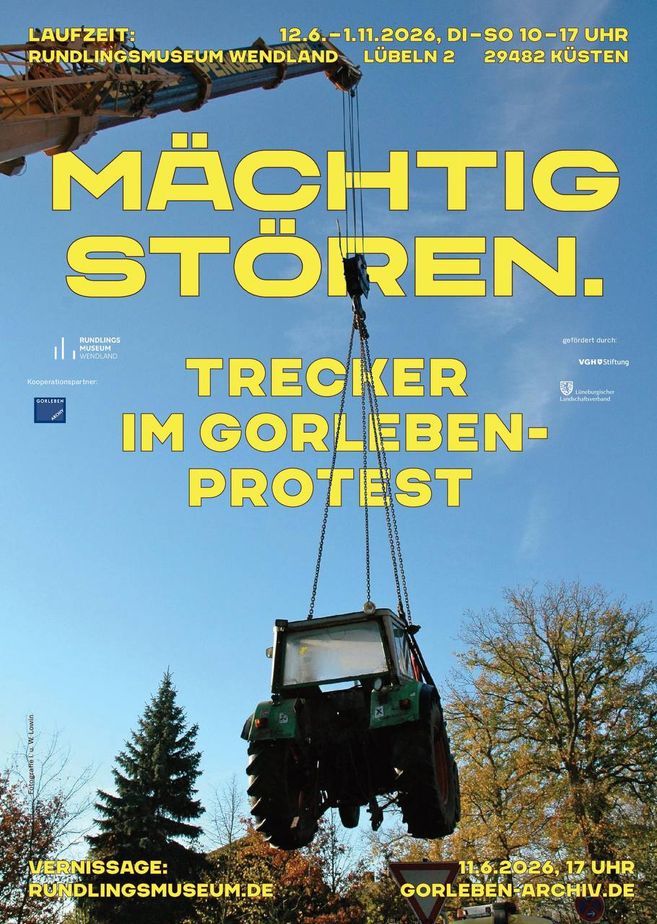 Ein Traktor wird von einem Kran in die Luft gehoben, umgeben von Bäumen und blauem Himmel. Text informiert über eine Ausstellung im Rundlingsmuseum Wendland.