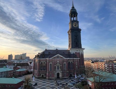 St. Michaelis Kirche in Hamburg bei Sonnenuntergang mit der Elbphilharmonie im Hintergrund.