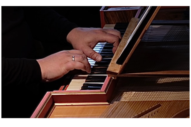 Nahaufnahme von Händen, die ein Cembalo spielen.