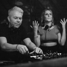 Zwei DJs bei einem Live-Set, einer bedient das Mischpult, die andere hebt die Hände.