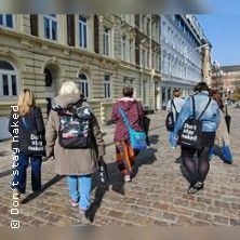 Eine Gruppe von Menschen geht auf einer gepflasterten Straße in Hamburg-Altona spazieren, mit Einkaufstaschen und historischen Gebäuden im Hintergrund.