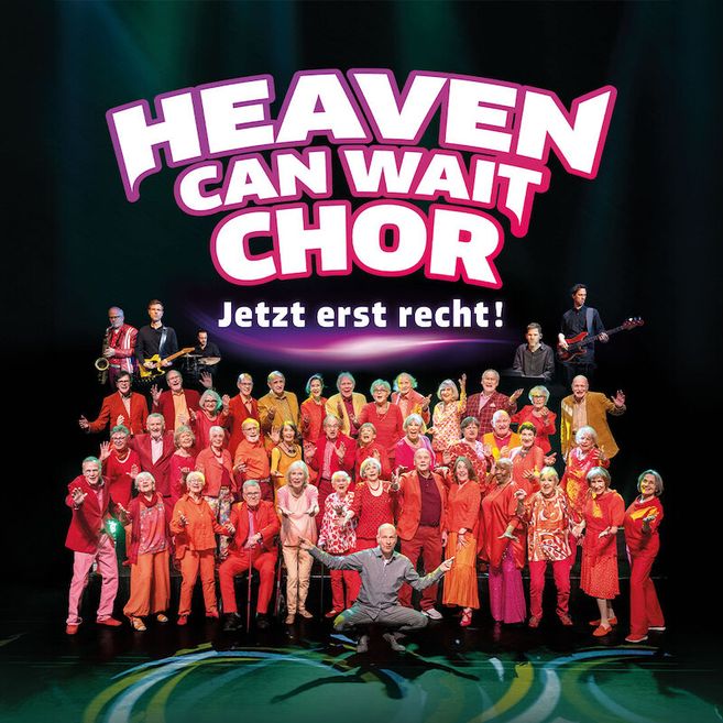 Eine Gruppe älterer Menschen in bunten Outfits posiert auf einer Bühne unter dem Schriftzug 'HEAVEN CAN WAIT Chor'.