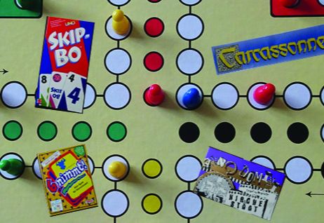 Ein Spielbrett mit Spielfiguren und Karten von Spielen wie Skip-Bo, Carcassonne und 6 nimmt!