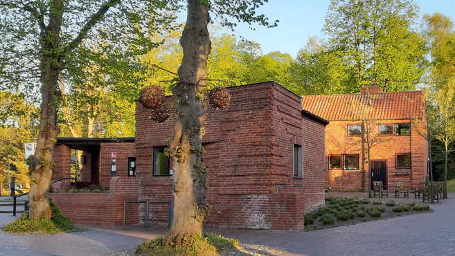 Backsteingebäude in Worpswede mit Bäumen im Vordergrund und Abendsonne.