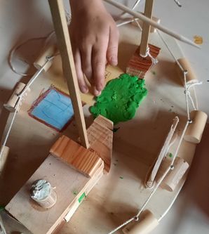 Kind baut Modellschiff aus Holz und Korken.