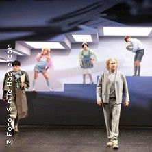 Theaterszene mit mehreren Schauspielern auf einer Bühne.