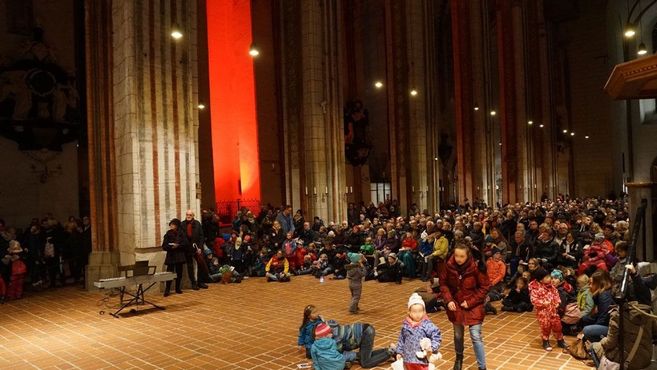 Menschenmenge in einer Kirche während eines Gottesdienstes mit roter Beleuchtung.
