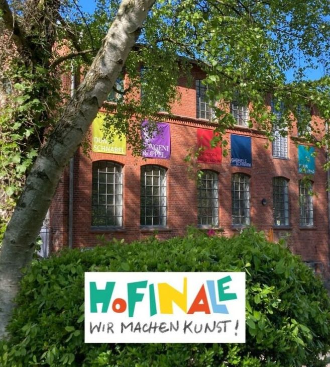 Backstein-Gebäude mit bunten Bannern und einem Schild mit der Aufschrift 'HoFinale - Wir machen Kunst!' im Vordergrund.