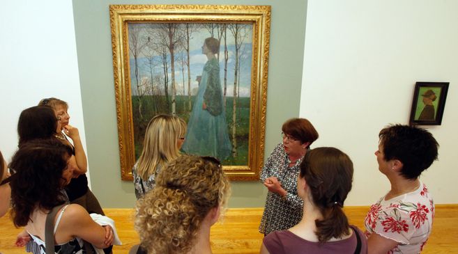 Eine Gruppe von Frauen betrachtet ein großes Gemälde in einem Museum.