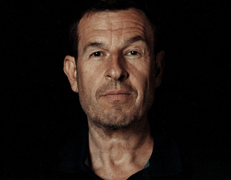 Porträt eines Mannes vor schwarzem Hintergrund.