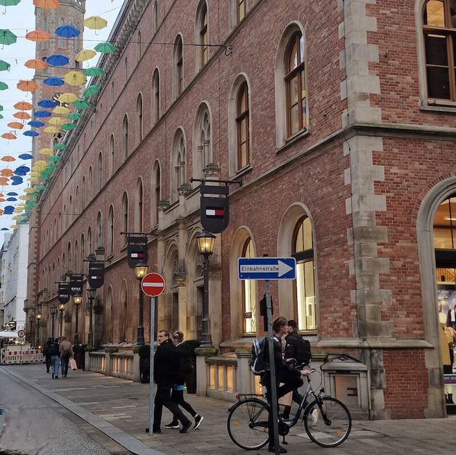 Historisches Gebäude in Hamburg mit bunten Regenschirmen über der Straße.