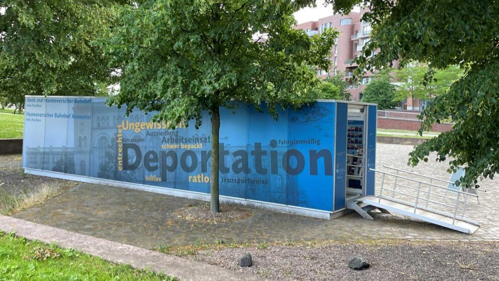 Gedenkort denk.mal Hannoverscher Bahnhof mit blauer Wand und Texten zur Deportation.