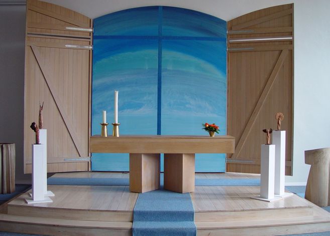 Innenansicht einer Kirche mit Altar, Kerzen und blauer Wanddekoration.