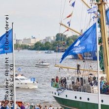 Segelschiff mit blauen Flaggen auf einem Fluss, umgeben von kleineren Booten.