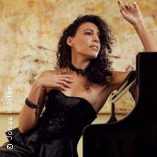 Eine Frau in einem eleganten schwarzen Kleid lehnt an einem Klavier.