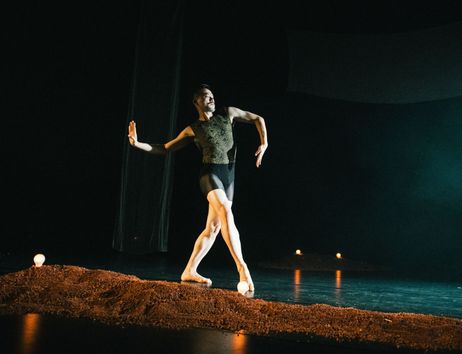 Ausschnitt aus der Tanzproduktion »Choreographing Story »Rama House«« von Chen Wu-kang und Pichet Klunchun. Eine performende Person bewegt sich in einer Ballett-Pose über die Bühne. Vor ihr ist ein kleiner erdartiger Hügel aufgescharrt.