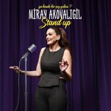 Frau auf Bühne mit Mikrofon, lila Vorhang im Hintergrund.